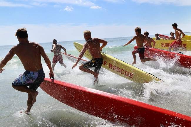 Seacoast area lifeguards race into the water with paddleboards Wednesday as part of the annual Northern New England Lifesaving Competition event held at Hampton Beach